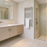 Salle de bains rénovée et lumineuse avec meuble vasque suspendu, douche vitrée moderne, sèche-serviettes et rangements intégrés.